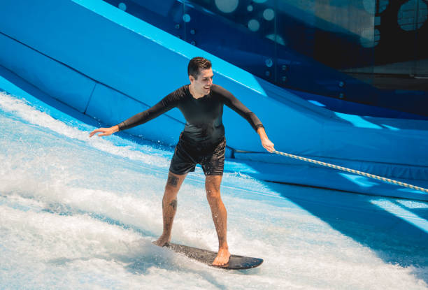 istock Young man surfing on a wave simulator at a water amusement park 1814383376