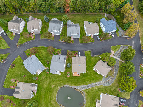 aerial drone view of neighborhood street with single family homes in autumn