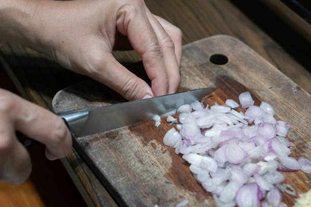 istock Woman's hand cut red onions on cutting board in home kitchen. 1814403955