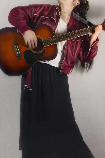 Young attractive female playing guitar in western style....