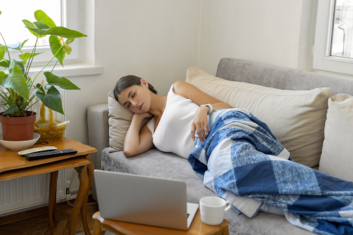 Woman sleeping under blanket on sofa