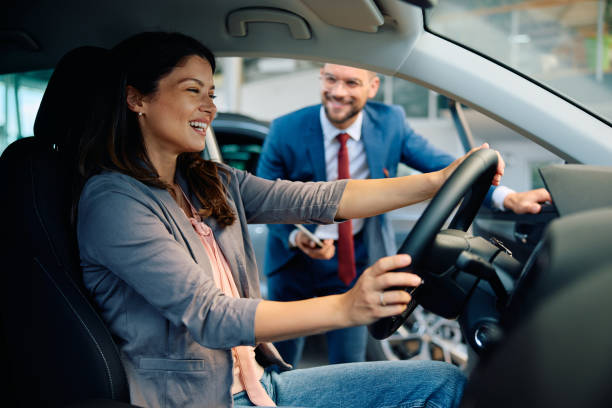 istock Happy woman testing a new car in showroom. 1814506414
