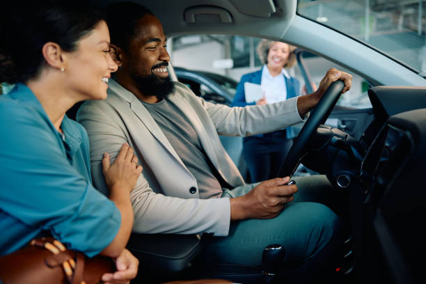 istock Happy multiracial couple testing new car in showroom. 1814511288
