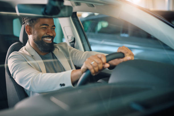 istock Happy black man testing new car in showroom. 1814512880