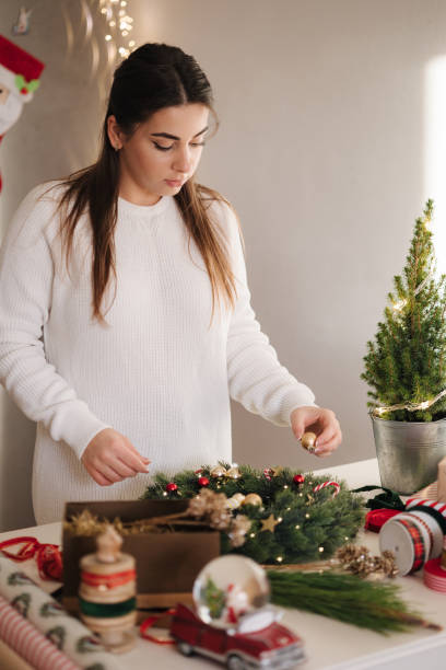istock Attractive woman making Christmas wreath using fresh pine branches and festive decorations. Christmas mood 1814513436
