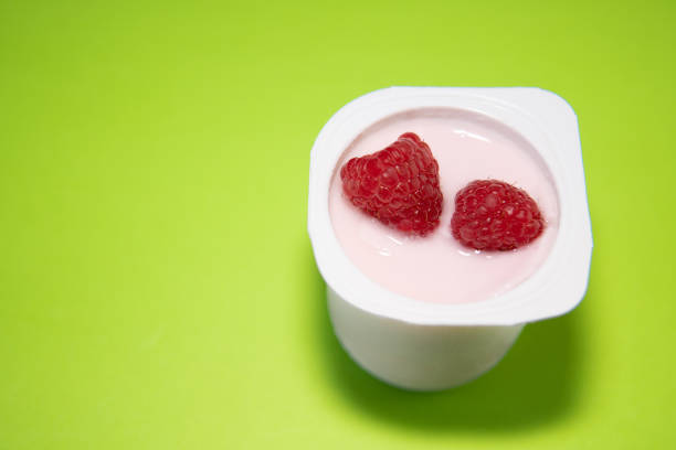 glass of yoghurt, with red raspberries on green background