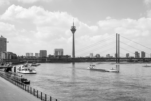 Dusseldorf, Germany - June 2, 2022: The Rhine river and Dusseldorf city skyline with TV tower and bridge in North Rhine-Westphalia, Germany. Black and white photography.