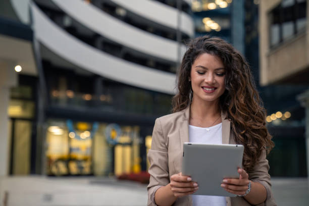 istock Beautiful smiling businesswoman looking contemplative while using a digital tablet outdoors 1814575496