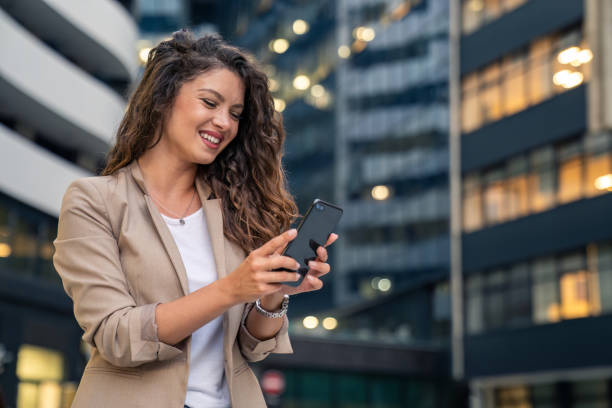 istock Happy smiling confident businesswoman standing using smartphone for texting, cellphone apps for work outside 1814580223
