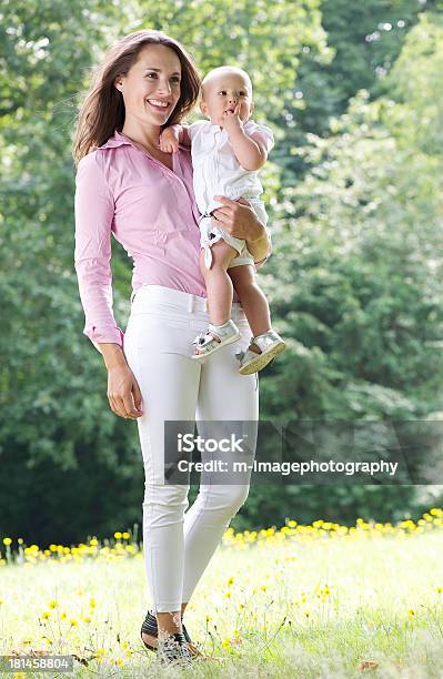 Photo libre de droit de Belle Femme Souriante Et Tenant Un Bébé Dans Le Parc banque d'images et plus d'images libres de droit de 12-17 mois