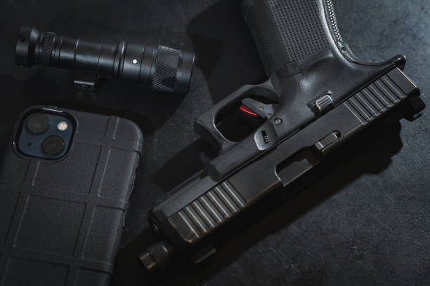 istock Self-defense equipment, 9mm pistol, cell phone and flashlight. 1814602695