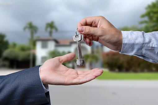 Handing Over the House Keys in Front of a Beautiful New Home.