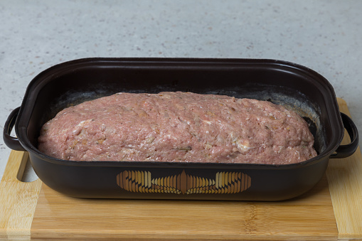 Raw meatloaf in the shape of a donut is ready for baking.