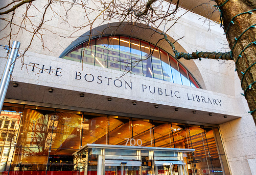 Halifax Central Library bookshelves near entrance with stairs to second floor in background.