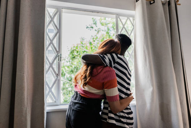 istock Couple embracing and looking at the view through window at hotel 1814647049