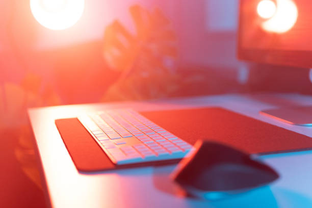 istock Close-up shot of computer keyboard and mouse on the table under neon lights 1814657968
