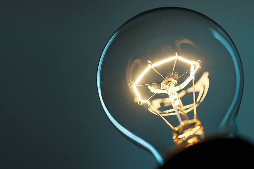 Glowing light bulb closeup with copy space on twilight blue background