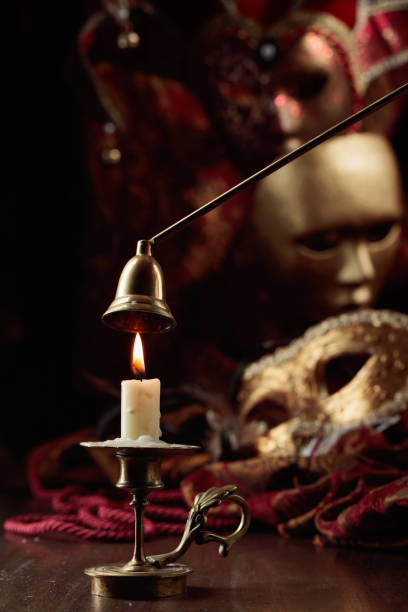 istock Burning candle in an old brass candlestick and carnival masks. 1814715301