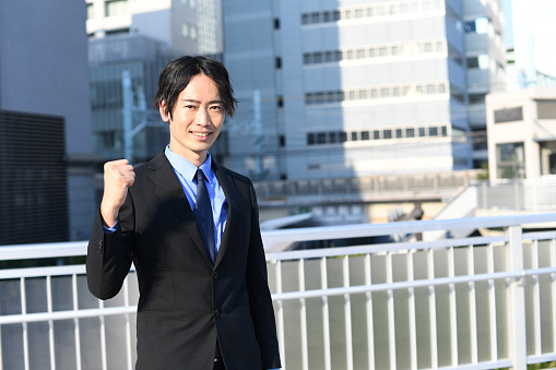 Asian businessman wearing a suit doing a fist pump outdoors