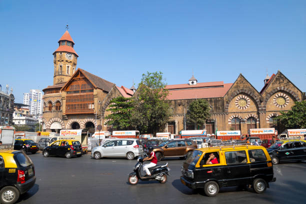 21st January, 2020 - Mumbai, India: This editorial image captures the exterior of Crawford Market, one of Mumbai's most famous and historic markets, located in the southern part of the city. Known for its Norman and Flemish architectural style, the market is a bustling hub of activity. The photograph shows locals going about their daily business, with the market's facade serving as a backdrop to the vibrant urban life. Shoppers are seen entering and exiting the market, some negotiating with street vendors, while others carry bags full of goods. The image aims to depict Crawford Market as a vital part of everyday life in Mumbai, highlighting its role as a cornerstone of the local community and a symbol of the city's rich cultural and architectural heritage.
