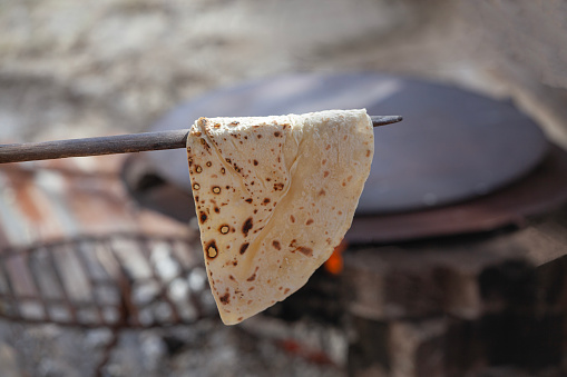 The woman makes and bakes Turkish style flatbread.