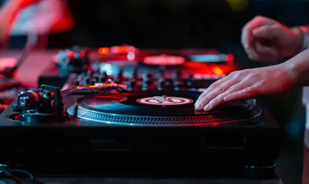 Hip hop dj scratches a record on turntable in night club