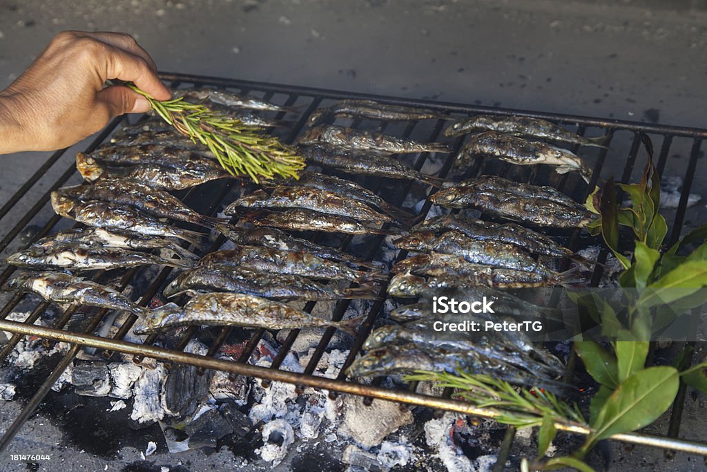 Oiling fresh Mediterranean fishes on BBQ Fresh Mediterranean fishes on traditional BBQ fireplace, oiling with virgin olive oil, selective focus Barbecue - Meal Stock Photo