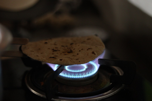 A Roti or chapati being cooked on the blue LPG flame