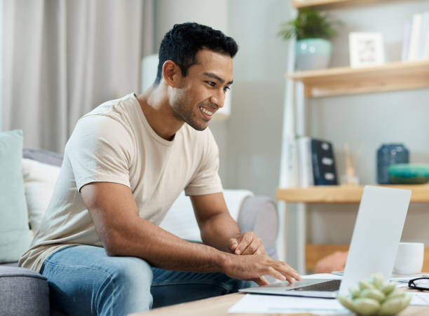 istock Laptop, typing and man on sofa for remote work, working from home and freelance career. Happy, living room and person on computer writing email for website, online project and internet research 1814772090