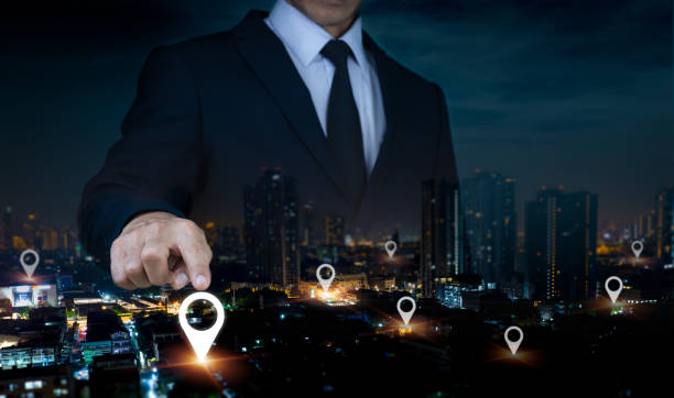 istock Pin the address position on a mobile app or GPS map. Man's hand is double exposed as he searches for a certain location on a nighttime cityscape with a tablet while using a laptop. 1814808058