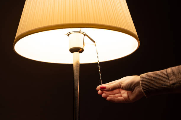 istock woman's hand turns on the floor lamp. 1814820339