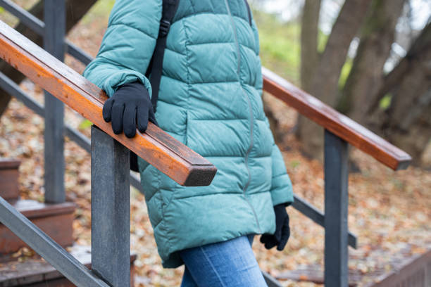 woman holding onto railing while going down stairs in rainy weather. woman holding the handrail of the stairs