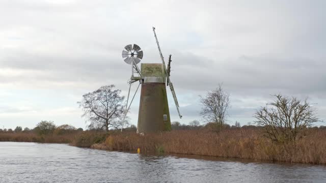 Abandoned and rundown windmill on the river bank