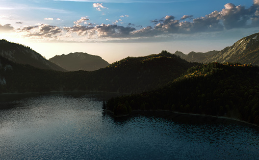 Mountain lake surrounded by forested mountains during autumn at sunrise.