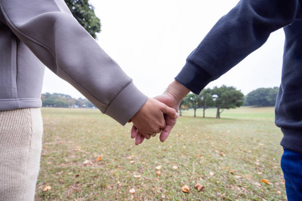 istock Couple holding hands in public park 1814844477