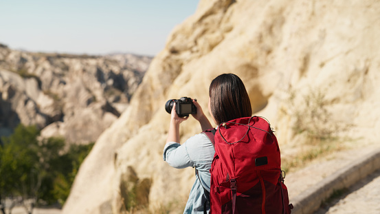 An Asian female tourist hiker videographer photographer is capturing the beauty of Cappadocia with her camera in Türkiye Turkey.