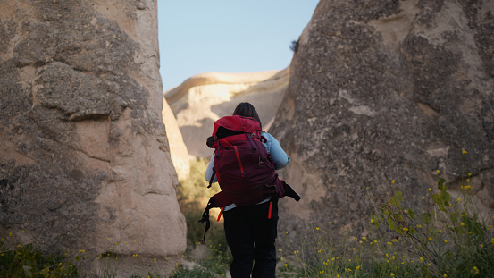 An Asian female backpacker tourist is enjoying hiking and walking in nature in Cappadocia Türkiye Turkey.