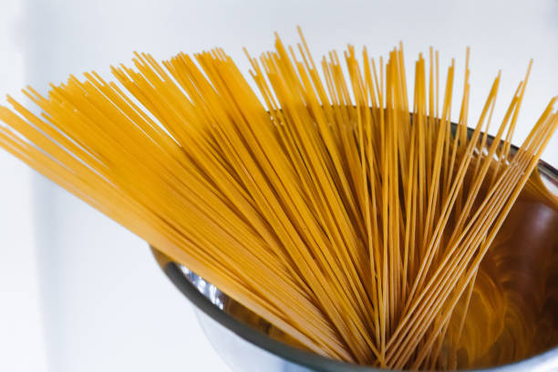 istock raw spaghetti in a metal bowl on white background. 1814857969