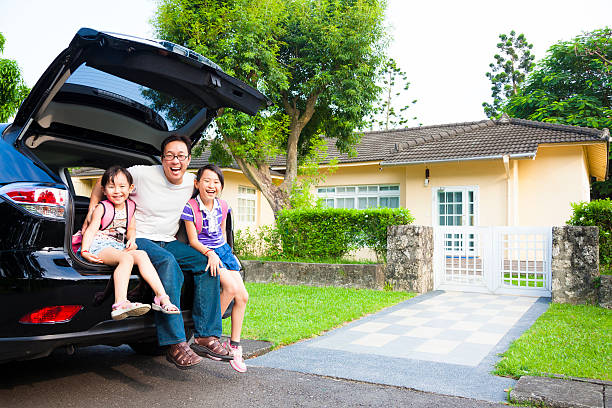 Family sitting on back of car in front of house happy family sitting in the car and their house behind family in car stock pictures, royalty-free photos & images