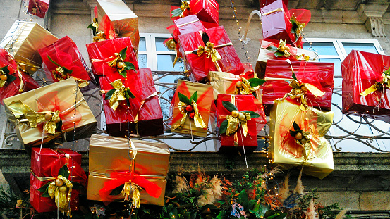 Christmas decorations over store front door, group of gift boxes, red and gold colored wrapping paper . Galicia, Spain.