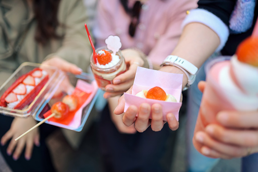 Group of people travel in osaka and buy Variety all of famaus dessert and sweets Bakeries sharing street food with friend in osaka japan