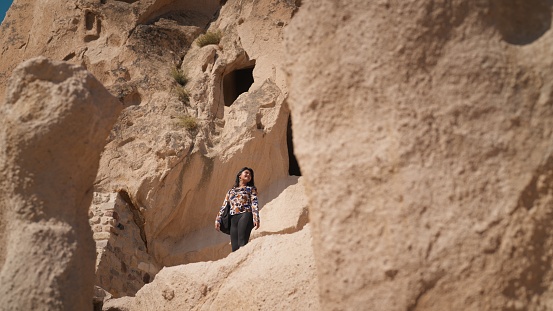 A multiracial beautiful young female tourist is hiking in nature in Cappadocia in Türkiye Turkey.