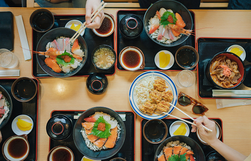 Group of tourist eating Premium fresh raw seafood mixed rice bowl Kaisen-donJapanese Rice with sashimi of tuna, Maguro, Otoro, salmon, squid and ikura (Salmon eggs)