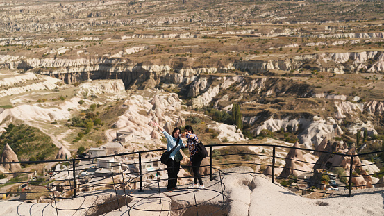 Two female tourist friends are using a mobile smart phone to take selfies and capture memories from their travel in Cappadocia Türkiye Turkey