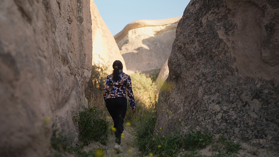 A multiracial beautiful young female tourist is hiking in nature in Cappadocia in Türkiye Turkey.