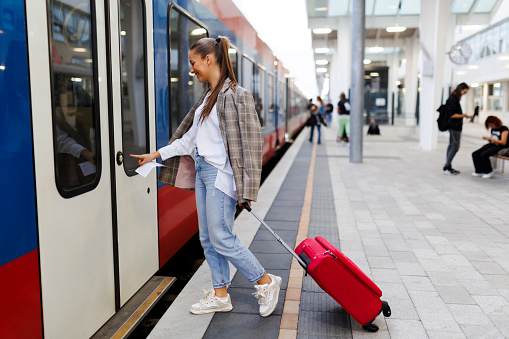 Young woman entering the train with a suitcase