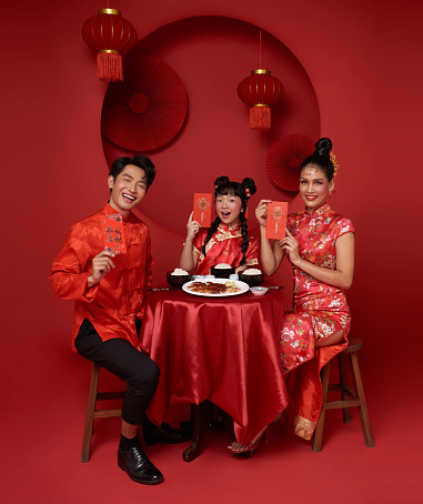 Happy Chinese new year. Asian family holding red lucky money envelopes and dinner food for prosperity celebration festival isolated on red decoration traditional festival background.