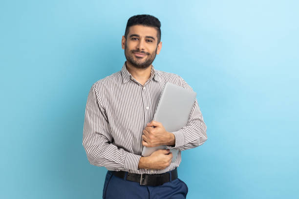 istock Businessman standing holding closed laptop or folder, looking at camera with positive expression. 1814899986
