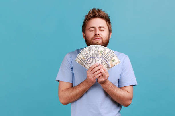 Man smelling earned dollar banknotes, enjoying success and big profit wealthy life, greedy for money stock photo