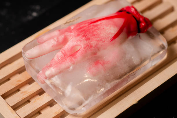 Horror on ice: A mock human hand frozen in a chunk of ice on a wooden cutting board, setting a chilling scene perfect for horror-themed designs Horror on ice: A mock human hand frozen in a chunk of ice on a wooden cutting board, setting a chilling scene perfect for horror-themed designs suspenseful stock pictures, royalty-free photos & images